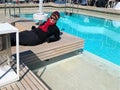 Happy woman dressed in winter clothing reclines poolside Royalty Free Stock Photo