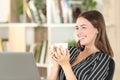 Happy woman drinking coffee looks away at home Royalty Free Stock Photo