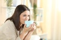 Happy woman drinking coffee sitting on a sofa at home Royalty Free Stock Photo