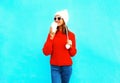 Happy woman drinks coffee in red sweater, hat on a blue Royalty Free Stock Photo