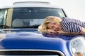 Happy woman driver embracing hood of car after detailing, polishing. Car insurance advertisement