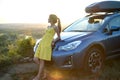 Happy woman driver in summer dress enjoying warm evening near her car. Travel and vacation concept Royalty Free Stock Photo