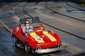 Happy woman driving a miniature car at an amusement park ride during a fun family vacation. Royalty Free Stock Photo