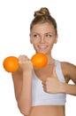 Happy woman with dumbbells fruits looking away