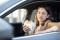 Happy woman eating a burger in the car Royalty Free Stock Photo