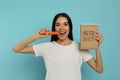 Happy woman eating carrot and holding notebook with words Keto Diet on turquoise Royalty Free Stock Photo