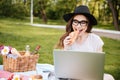 Happy woman eating croissant and using laptop outdoors Royalty Free Stock Photo