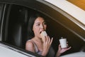 Happy woman eating food and drinking coffee while driving to work in the early morning Royalty Free Stock Photo