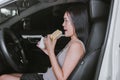 Happy woman eating food and drinking coffee while driving to work in the early morning Royalty Free Stock Photo