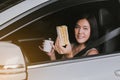 Happy woman eating food and drinking coffee while driving to work in the early morning Royalty Free Stock Photo