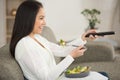 Happy woman eating fresh vegetable salad while watching tv Royalty Free Stock Photo