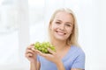 Happy woman eating grapes at home