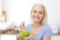 Happy woman eating grapes on kitchen Royalty Free Stock Photo
