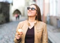 Happy woman eating and holding ice cream cone in city street. Royalty Free Stock Photo
