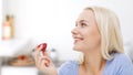 Happy woman eating strawberry on kitchen