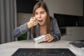 Happy woman enjoying a delicious takeaway lunch at home. A beautiful girl sits at a table and eats from a food container Royalty Free Stock Photo