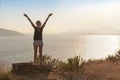 Happy woman enjoying freedom with open hands on the rock on sea background.