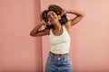 Happy woman enjoying music while standing against pink wall looking at camera Royalty Free Stock Photo