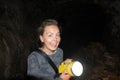 Happy woman explorer holds a flashlight while caving and spelunking underground at Lava Beds National Monument in California