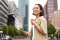 Happy woman exploring the city. Young korean girl holds tablet, drinks coffee and walks along street with big smile on Royalty Free Stock Photo