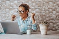 Happy woman exult and celebrate in front of a laptop after receiving a notification or email message. Overjoyed people working on