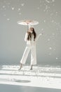 happy woman in fashionable winter sweater and scarf standing under japanese umbrella, snow falling Royalty Free Stock Photo