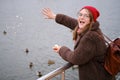 Happy woman feeding ducks on winter pond Royalty Free Stock Photo