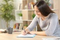 Happy woman filling out form on a desk at home