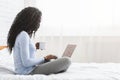 Happy woman flirting online on laptop in bed Royalty Free Stock Photo