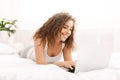 Happy woman flirting online on laptop in bed Royalty Free Stock Photo