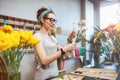 Happy woman florist holding flowers and making bouquet in shop Royalty Free Stock Photo