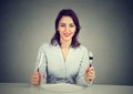 Happy woman with fork and knife sitting at table with empty plate Royalty Free Stock Photo