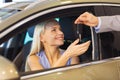 Happy woman getting car key in auto show or salon Royalty Free Stock Photo