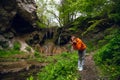 Happy woman, girl in a bright sweater is posing with Burta Gural waterfall on the Sudenytsya River, Derzhanivka Khmelnytskyi