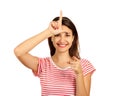 A happy woman gives a sign of the loser on his forehead, looking at you and pointing his finger at the camera. emotional girl isol Royalty Free Stock Photo