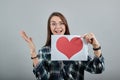 Happy woman with glasses holding a piece of paper with red heart, hand gestures Royalty Free Stock Photo
