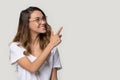 Happy woman in glasses pointing finger at copy space