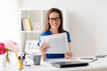 Happy woman in glasses reading newspaper at office Royalty Free Stock Photo