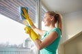 Happy woman in gloves cleaning window with rag Royalty Free Stock Photo