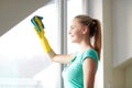 Happy woman in gloves cleaning window with rag Royalty Free Stock Photo