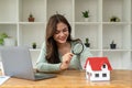 Happy woman hand holding magnifying glass and looking at house model, house selection, real estate concept. Royalty Free Stock Photo
