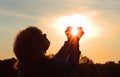 Happy woman and hands forming a heart shape with sunset silhouette, partial blurred, Royalty Free Stock Photo