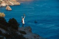 Happy woman with hands up posing on edge of cliff. Lifestyle change or goal achievement concept. Thirst for travel idea