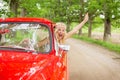 Happy woman hanging out of vintage car