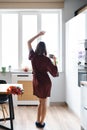 Woman having a coffee at home while dancing and enjoying flowers