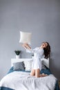 Happy woman having fun pillow throws enjoying funny activity on weekend at home