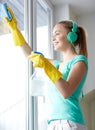 Happy woman with headphones cleaning window