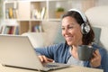 Happy woman with headphones watching video on laptop at home