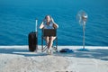 Happy woman in headset working on laptop, seascape on background. Lifestyle change idea. Business travelling concept