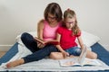 Happy woman with her daughter child, reading together a book a Royalty Free Stock Photo